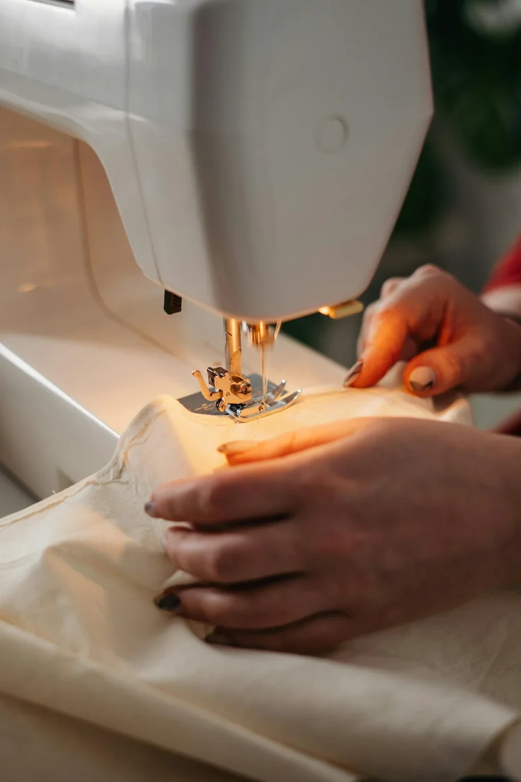 Detailaufnahme einer Nähmaschine bei der Arbeit an hellem Stoff